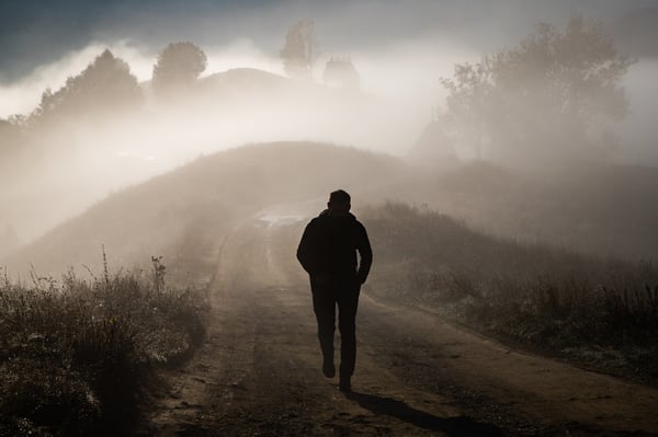 Man on a walk in the hills with lots of fog around him and the landscape