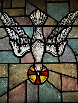 Stained glass window depicting the holy spirit coming down in the form o f a dove