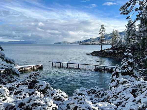 Overlooking to docks in Lake Tahoe with fresh snow on the trees and mountains in the distance